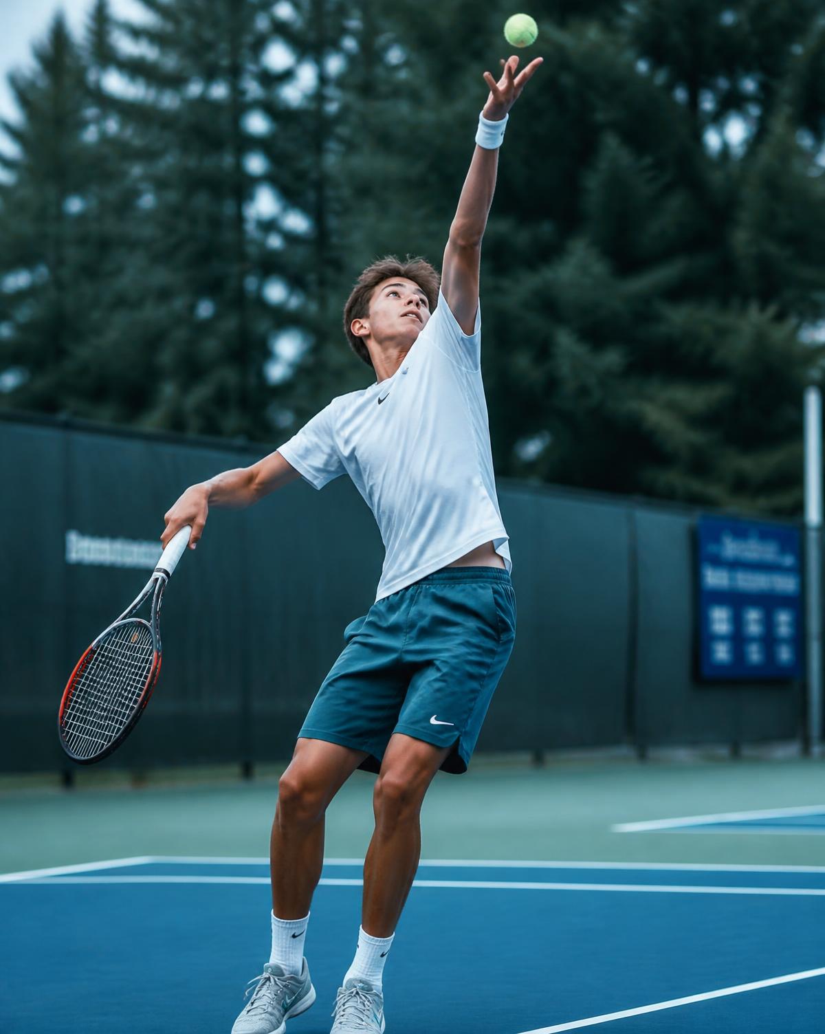 Junior player striking a serve on a blue-green court